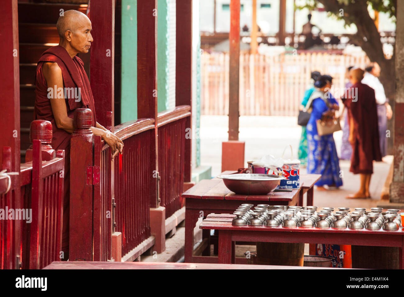 Un senior monaco attende per giovani monaci a immettere l'area da pranzo e di un monastero durante una cerimonia di Alms a Mandalay, Myanmar. Foto Stock