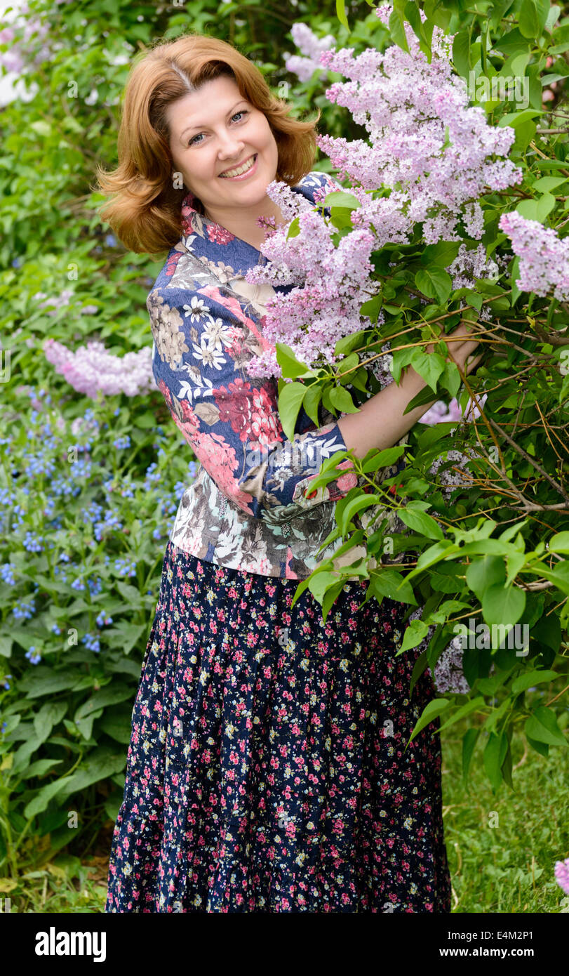 Donna di mezza età vicino a fioritura lilla Foto Stock
