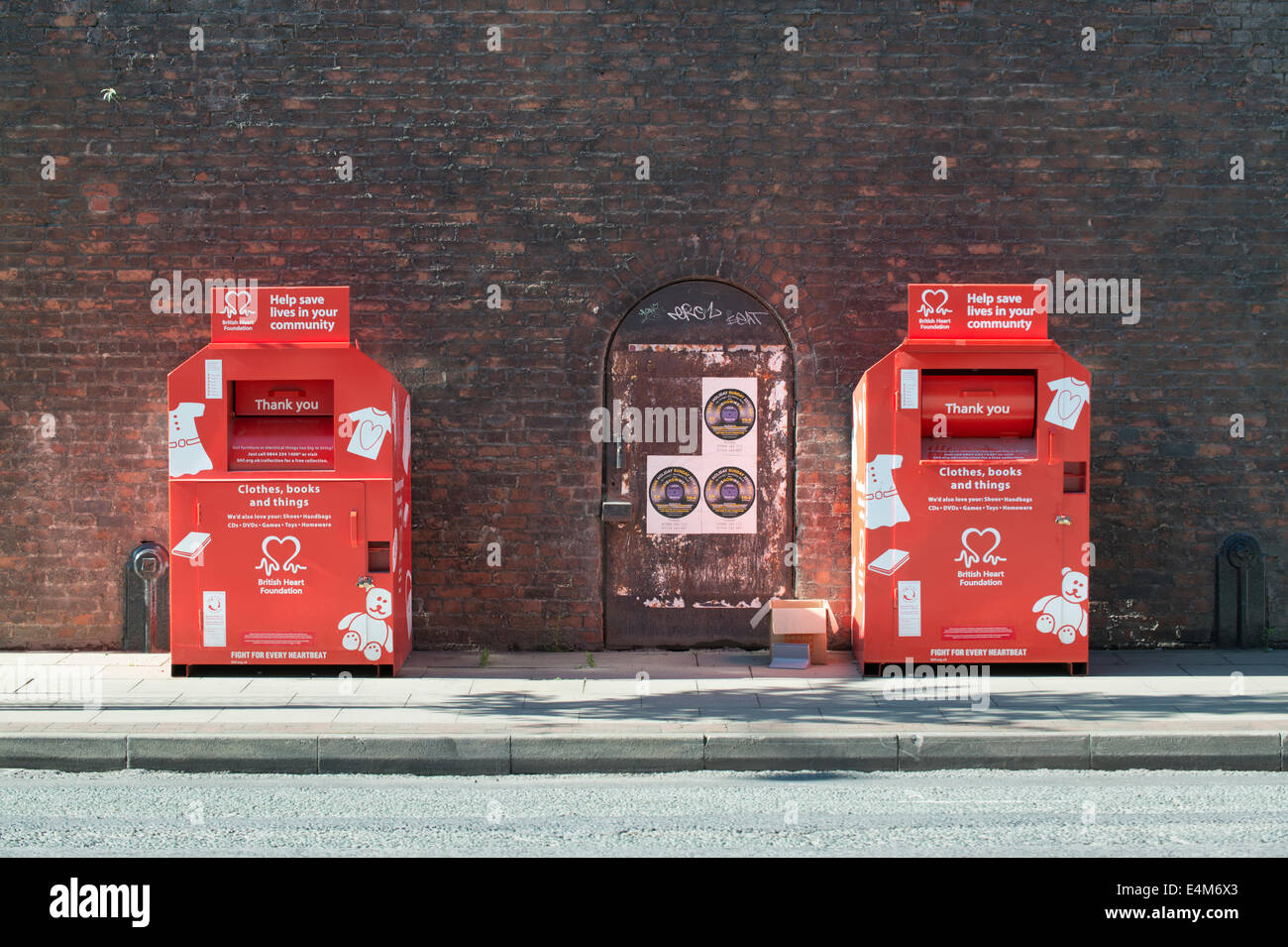 Due British Heart Foundation contenitori per il riciclaggio usato scarpe e vestiti su Whitworth Street West in Manchester. Foto Stock