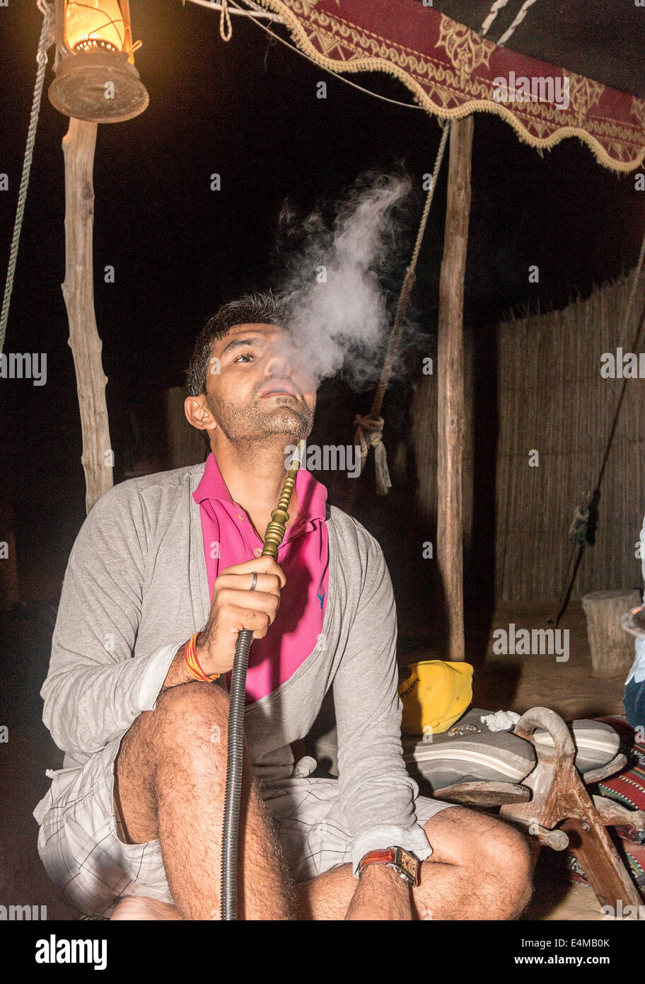 Ospite tenta di eseguire narghilè, un popolare Medio Orientale strumento di fumare per vaporizzare e fumare tabacco aromatizzato Foto Stock