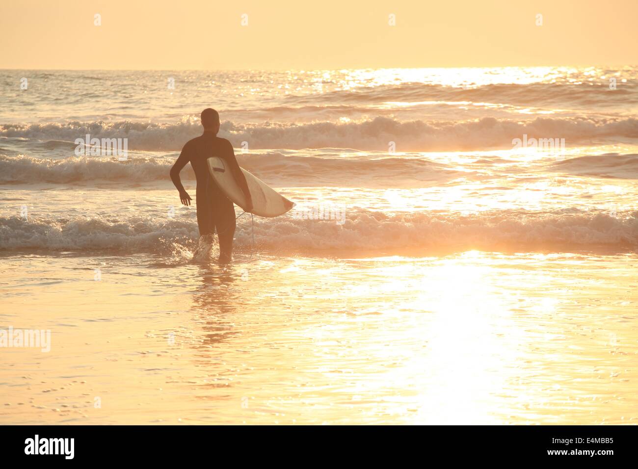 Un surfista in onde al tramonto sulla spiaggia dell'oceano di San Francisco, California Foto Stock