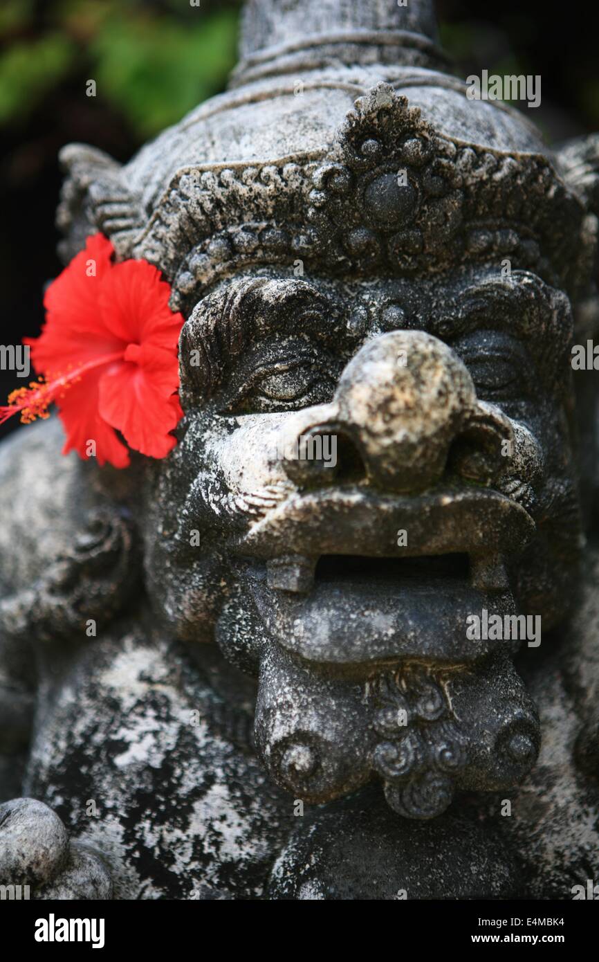 Statua balinese e fiori di ibisco Foto Stock