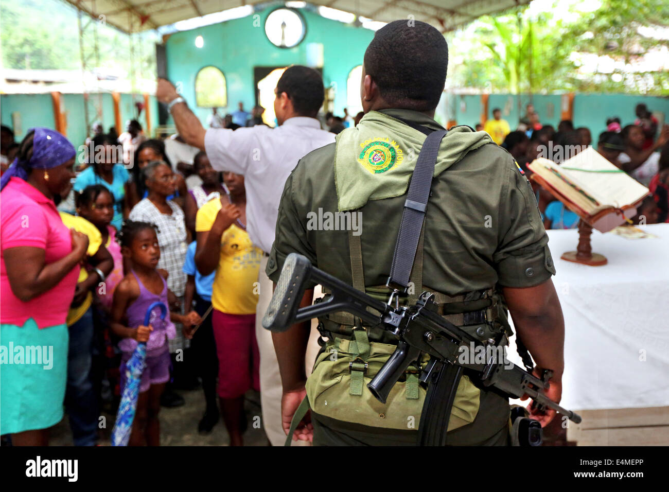 Armati pesantemente poliziotto nazionale guardia dietro l altare maggiore dopo la messa in servizio di una chiesa in Choco Provincia, Colombia Foto Stock