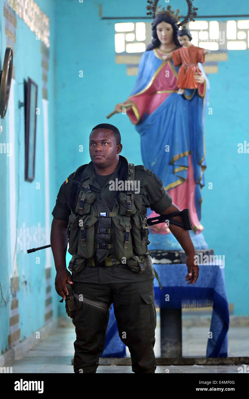 Armati pesantemente poliziotto nazionale guardia sotto una statua della Vergine Maria, la messa in servizio di una chiesa in Choco Provincia, Colombia Foto Stock