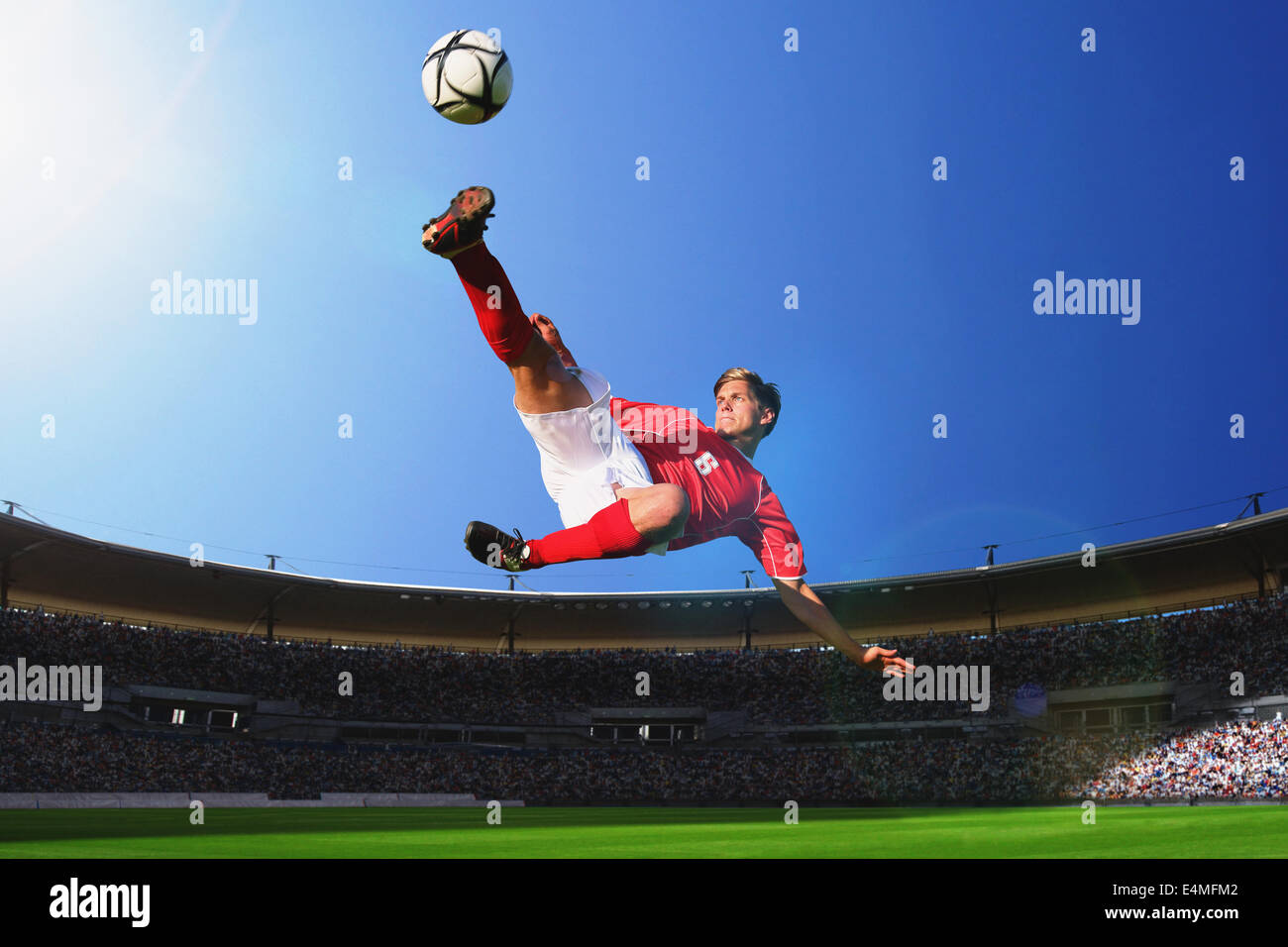 Giocatore di calcio calciare il pallone in Mid-Air Foto Stock