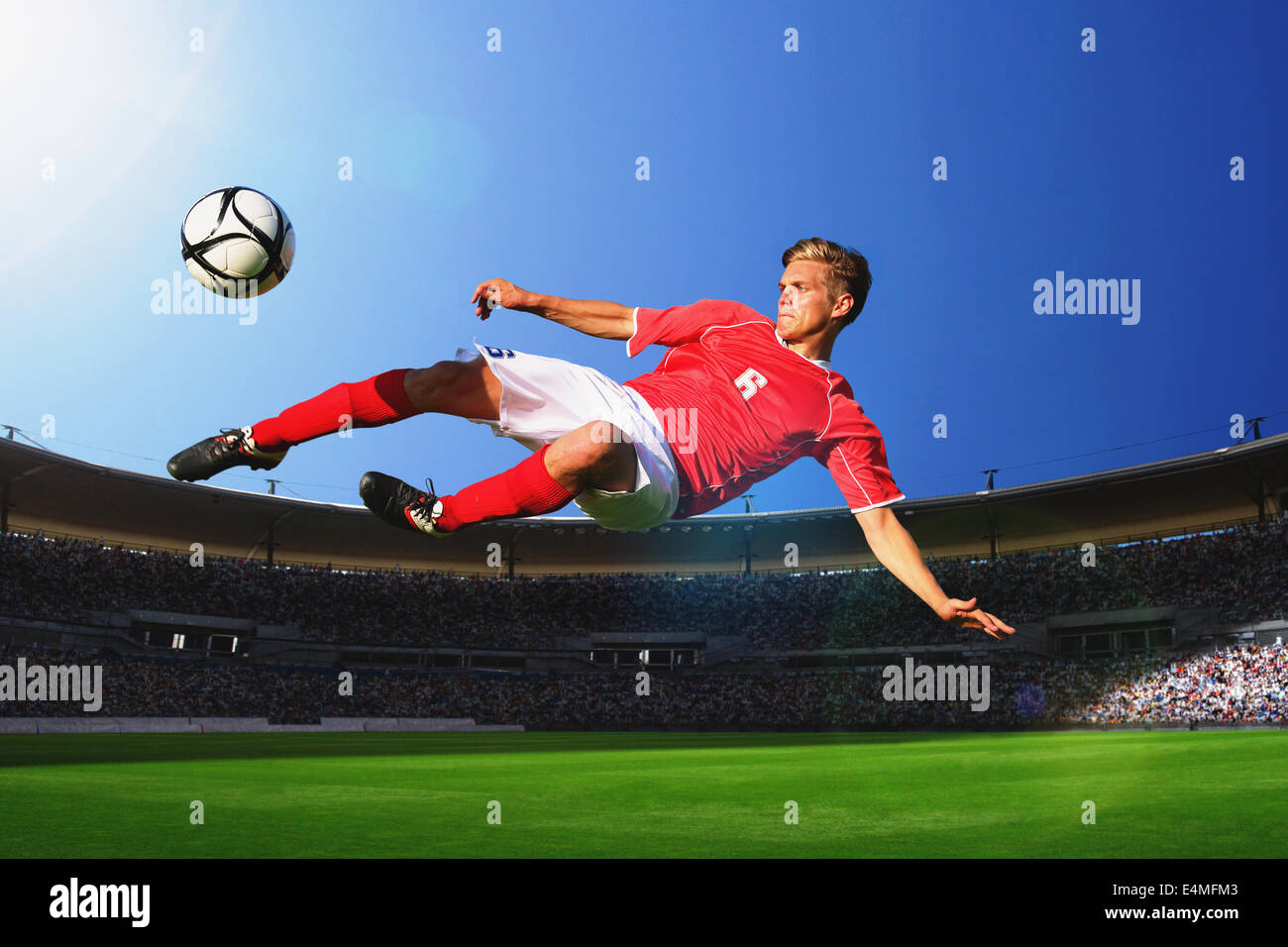 Giocatore di calcio calciare il pallone in Mid-Air Foto Stock