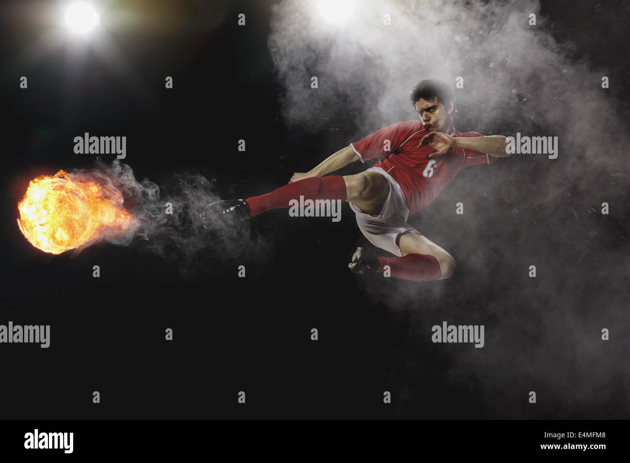 Giocatore di calcio calciare il pallone in Mid-Air Foto Stock