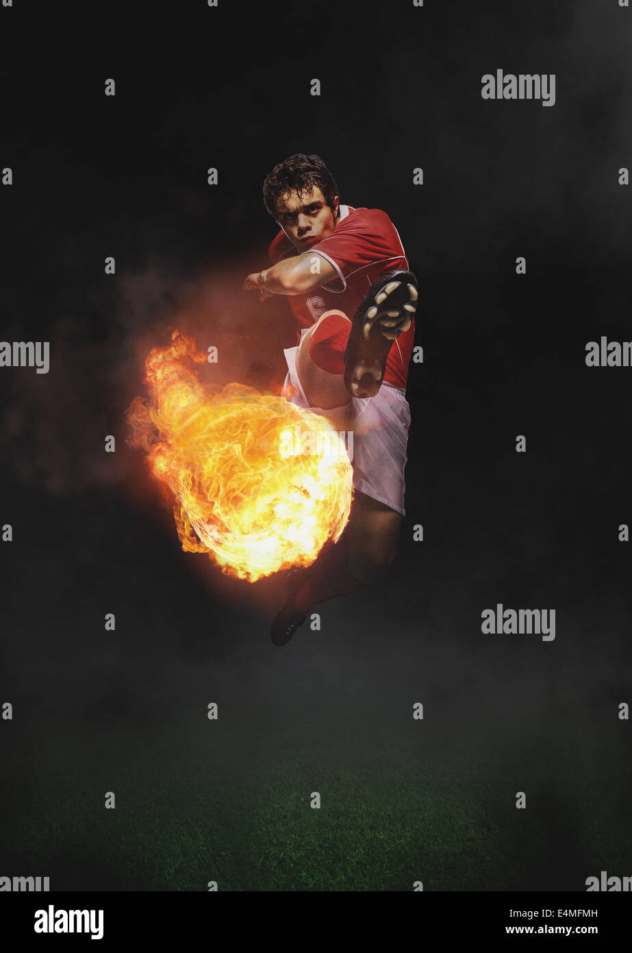 Giocatore di calcio calciare il pallone in Mid-Air Foto Stock