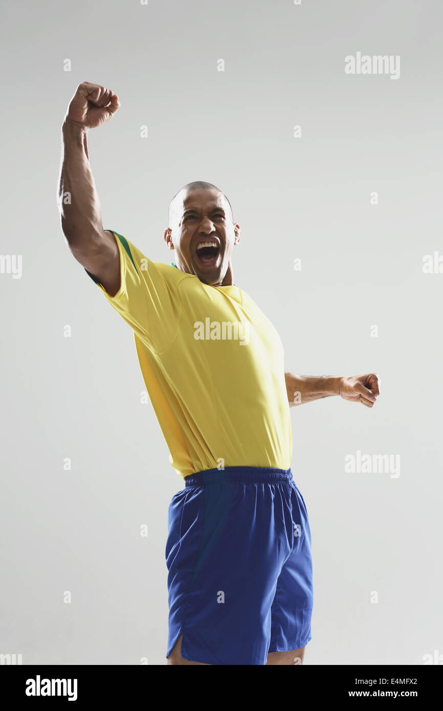 Giocatore di calcio in un giallo e blu uniforme in piedi contro uno sfondo bianco Foto Stock