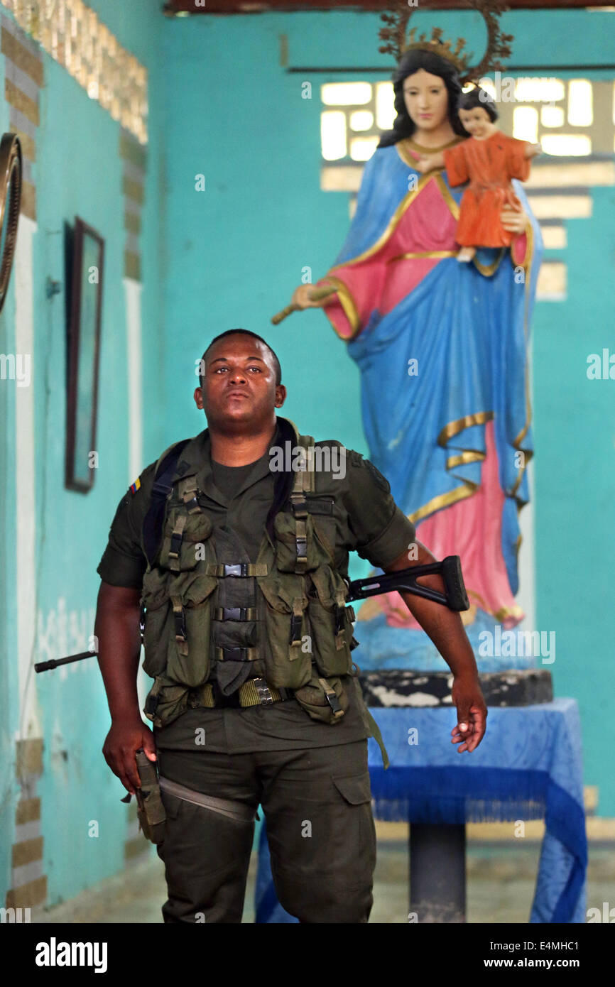 Armati pesantemente poliziotto nazionale guardia sotto una statua della Vergine Maria, la messa in servizio di una chiesa in Choco Provincia, Colombia Foto Stock