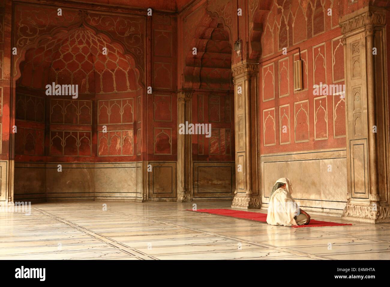 Un bianco incappucciati figura prega in una moschea di Delhi, India Foto Stock