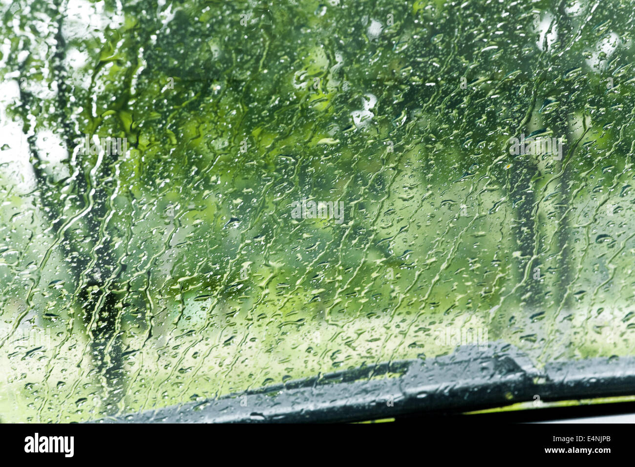 Le gocce di pioggia rotolare giù per un parabrezza di automobile Foto Stock