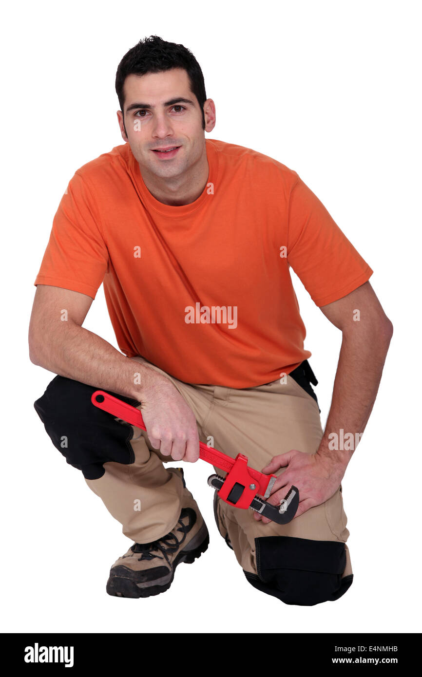 Inginocchiato tuttofare in possesso di una chiave a tubo Foto Stock