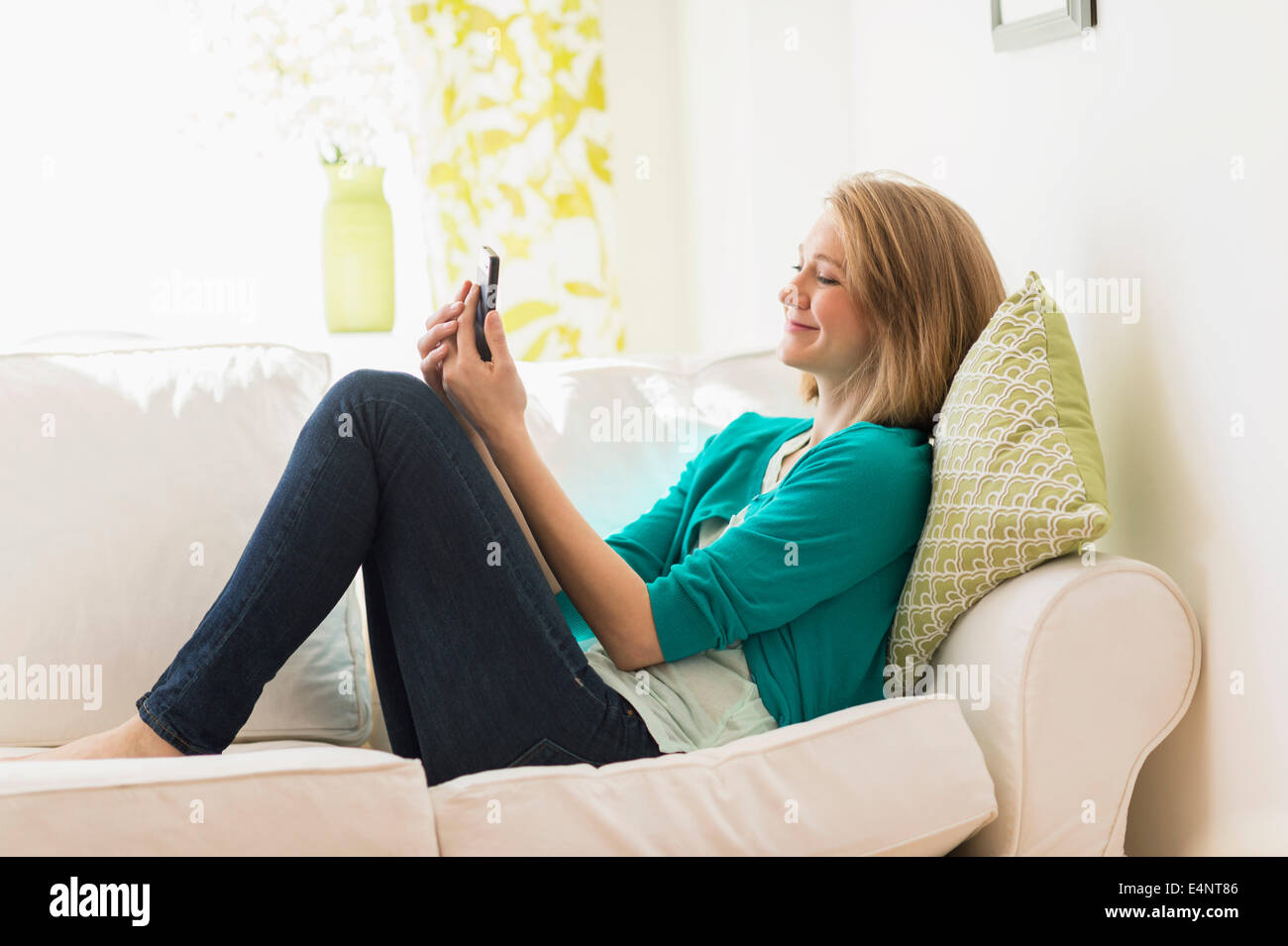 Ritratto di donna sul divano utilizzando smart phone Foto Stock