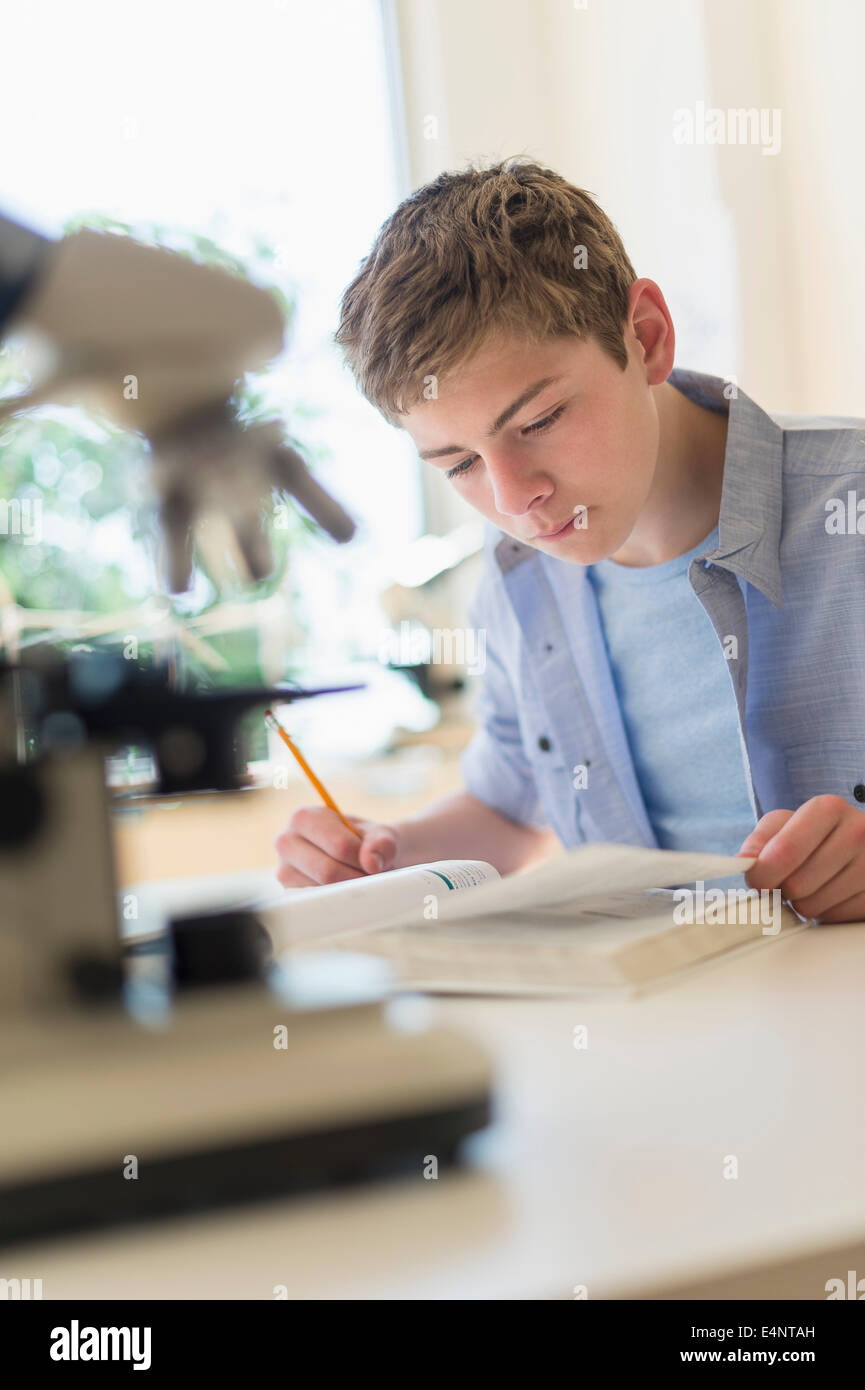 Ragazzo adolescente (16-17) lettura del libro in laboratorio Foto Stock