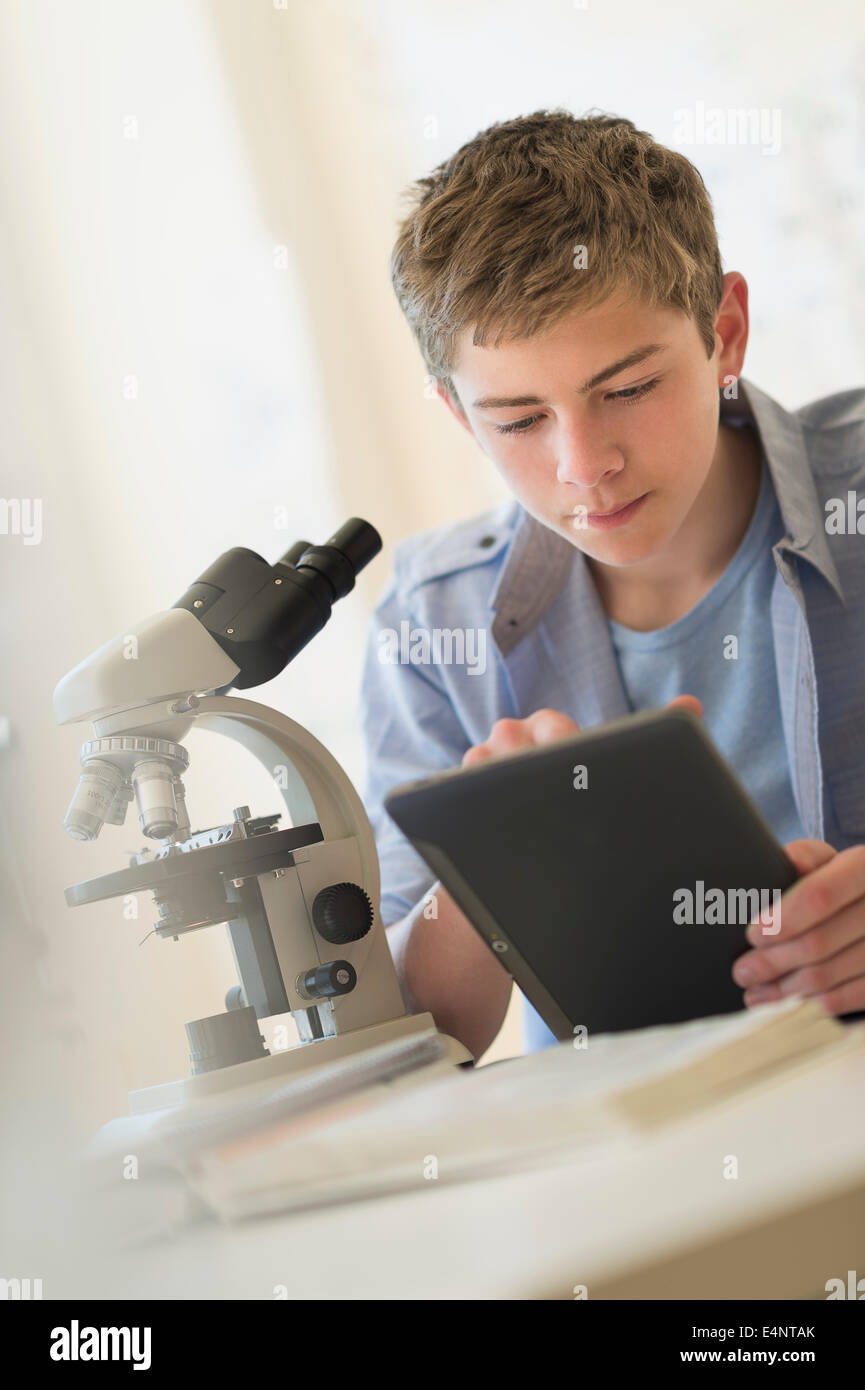 Ragazzo adolescente (16-17) utilizzando la tavoletta digitale in laboratorio Foto Stock