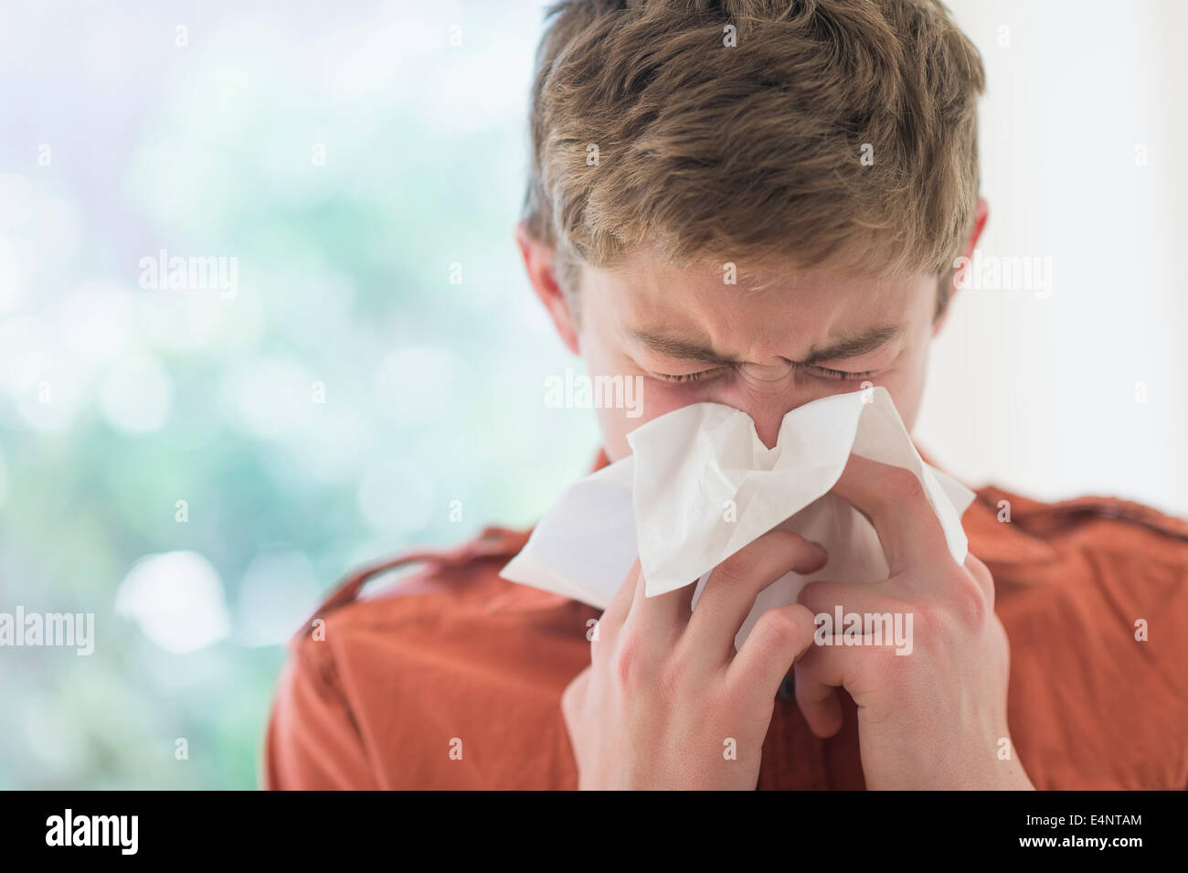 Ragazzo adolescente (16-17) che soffia il naso Foto Stock