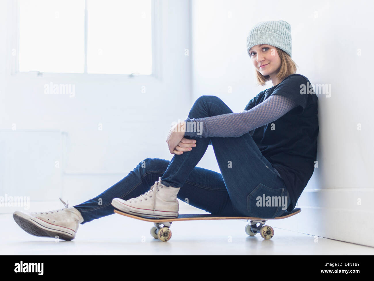 Ritratto di giovane donna seduta su skateboard Foto Stock