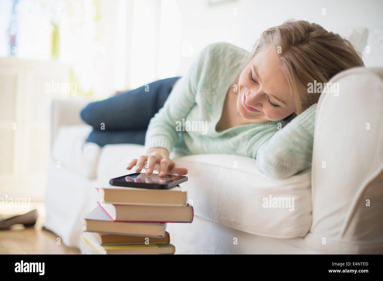 Donna sdraiata sul divano e con tavoletta digitale Foto Stock