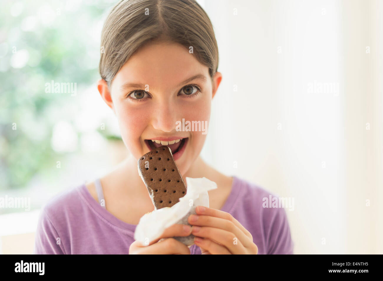 La ragazza (10-11) a mangiare il gelato a sandwich Foto Stock