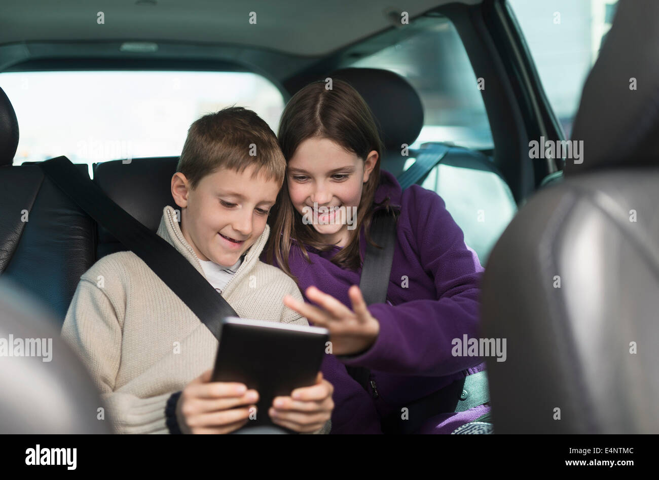 Un ragazzo e una ragazza (8-9, 10-11) utilizzando la tavoletta digitale in auto Foto Stock