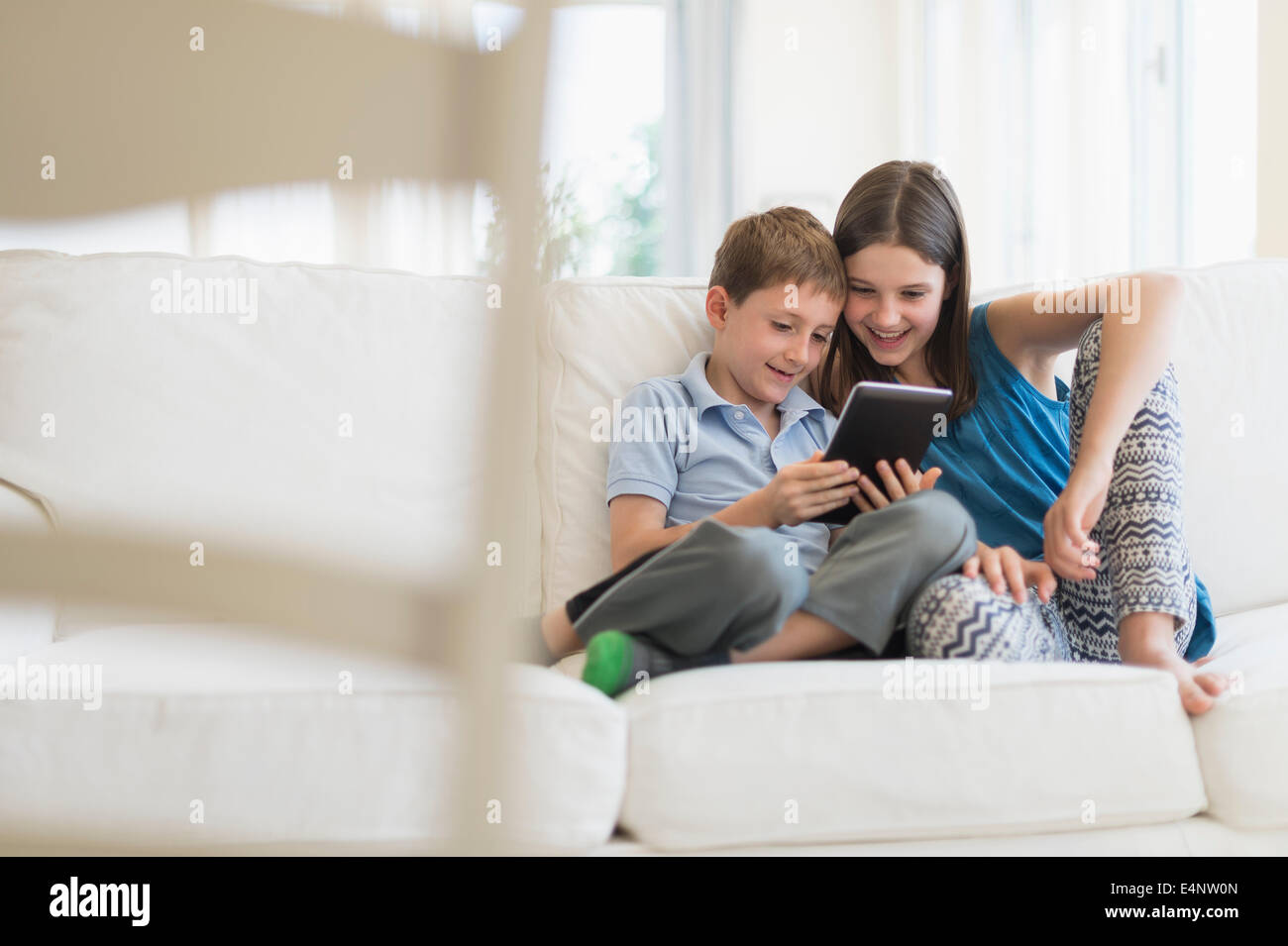 Un ragazzo e una ragazza (8-9, 10-11) seduto sul divano con tavoletta digitale Foto Stock