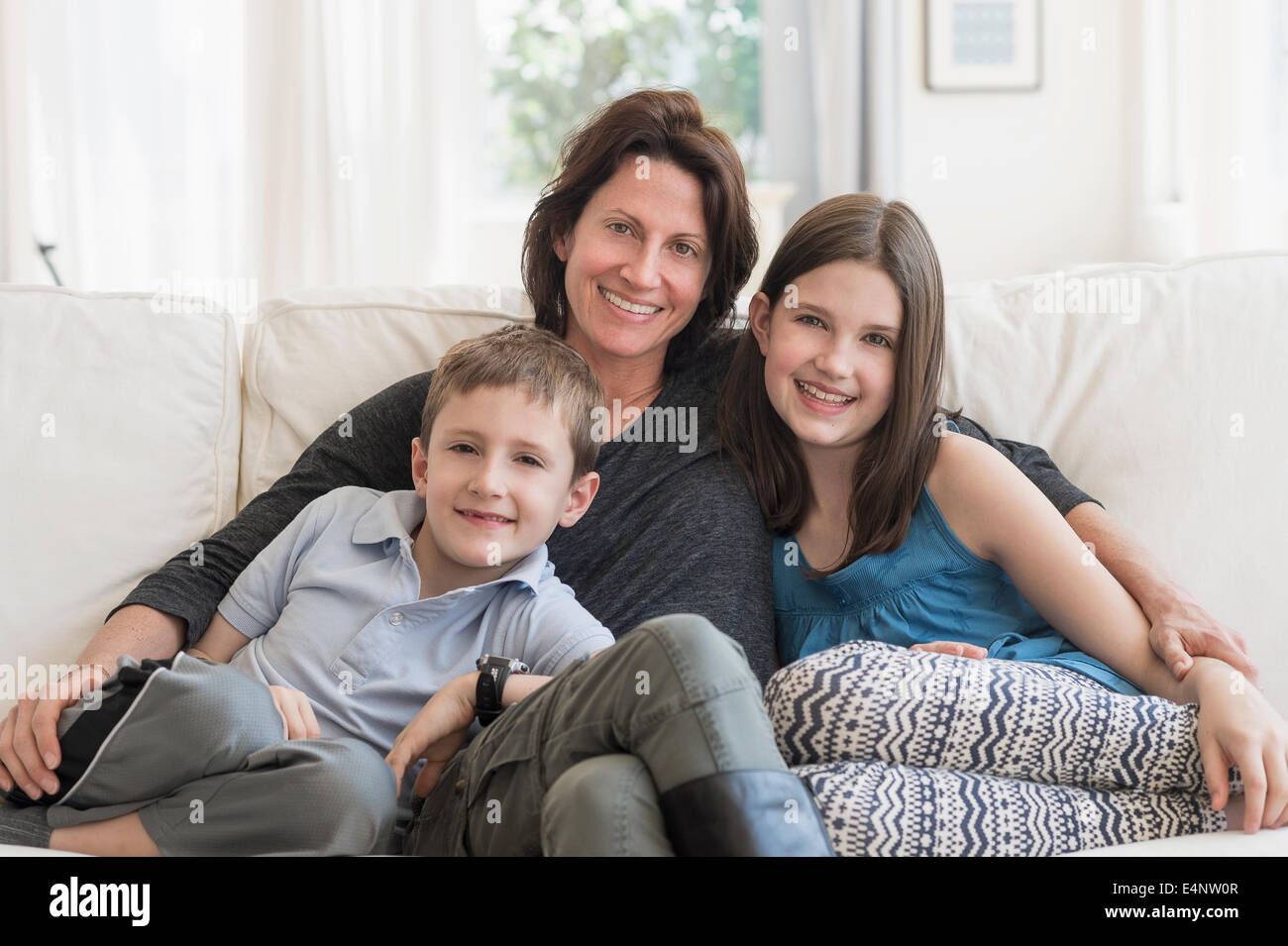 Madre e bambini (8-9, 10-11) seduto sul divano Foto Stock