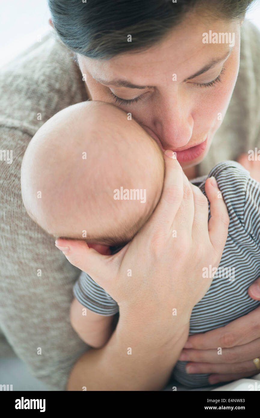 Close up di madre whispering in baby boy (2-5 mesi) ear Foto Stock