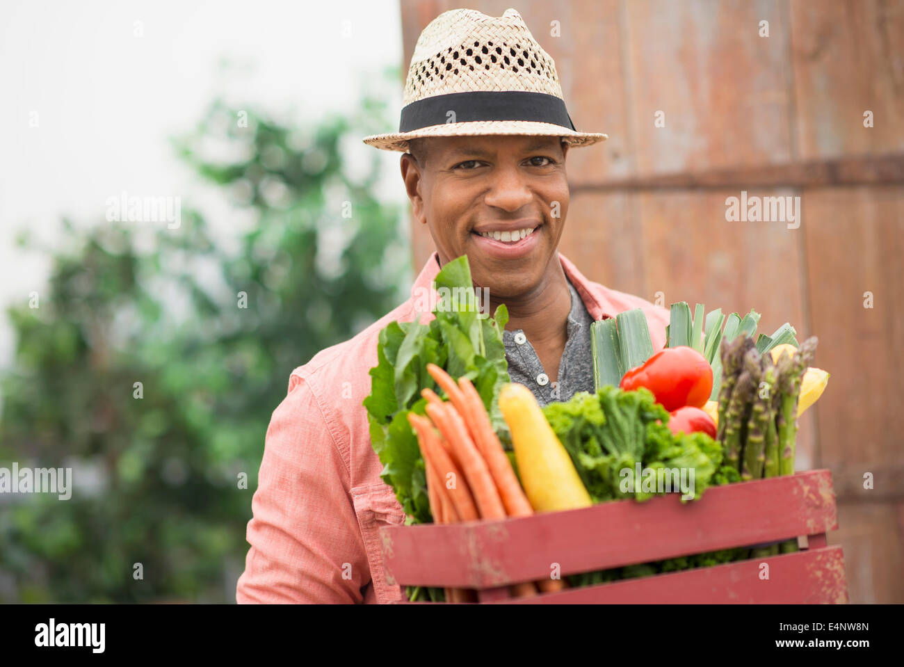 Ritratto di uomo che porta cassetta piena di verdure fresche Foto Stock