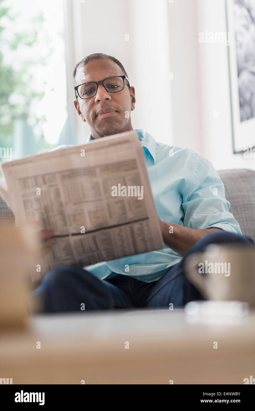 L'uomo la lettura di giornale sul divano Foto Stock