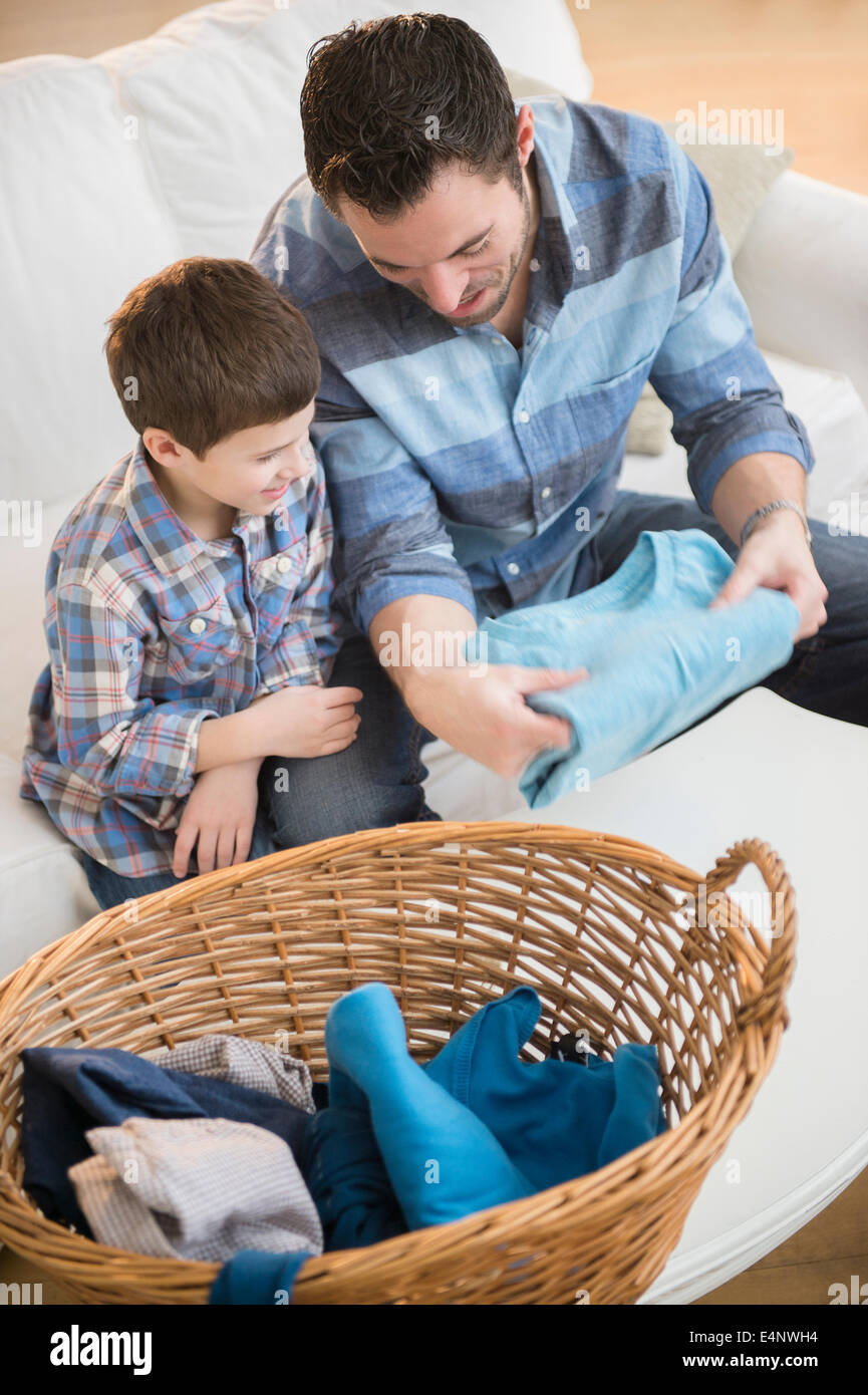 Il padre lo smistamento lavanderia con suo figlio (8-9) Foto Stock