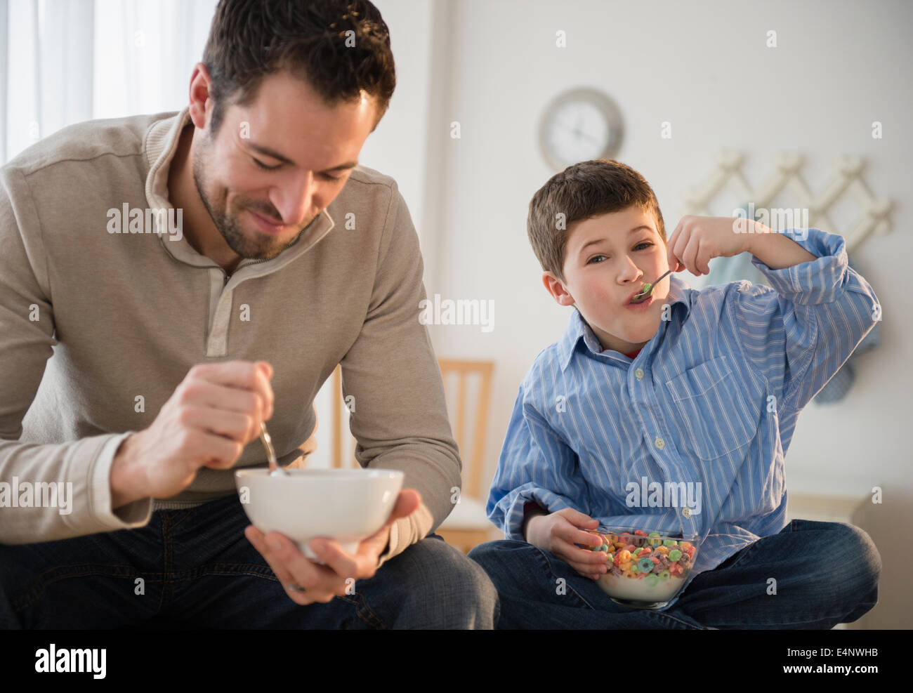 Padre e figlio (8-9) mangiare cereali per la prima colazione Foto Stock