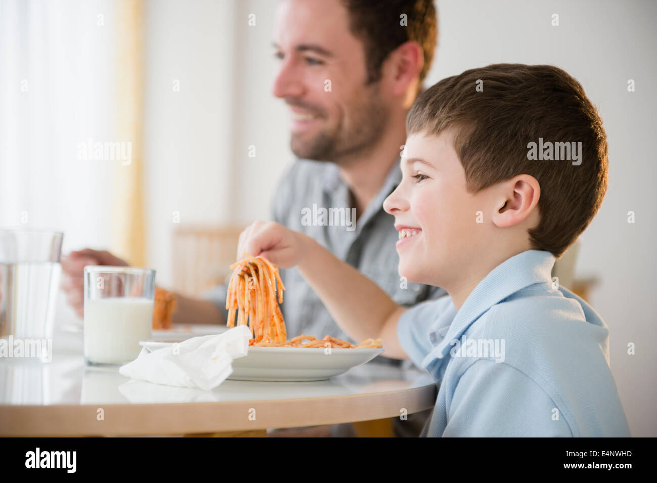 Padre e figlio (8-9) mangiare spaghetti Foto Stock
