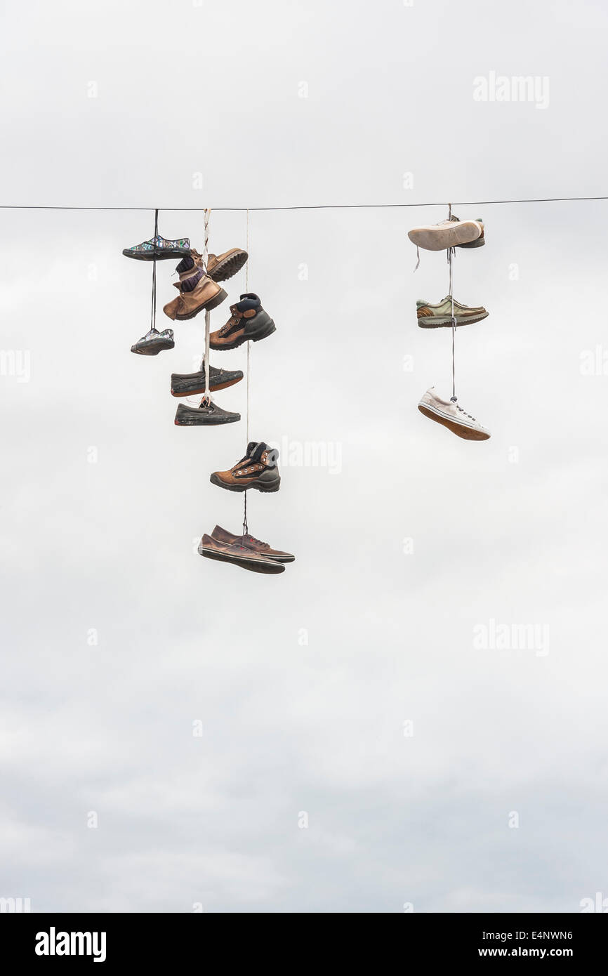Molti vecchi indossato stivali o scarpe appendere su un cavo elettrico Foto Stock