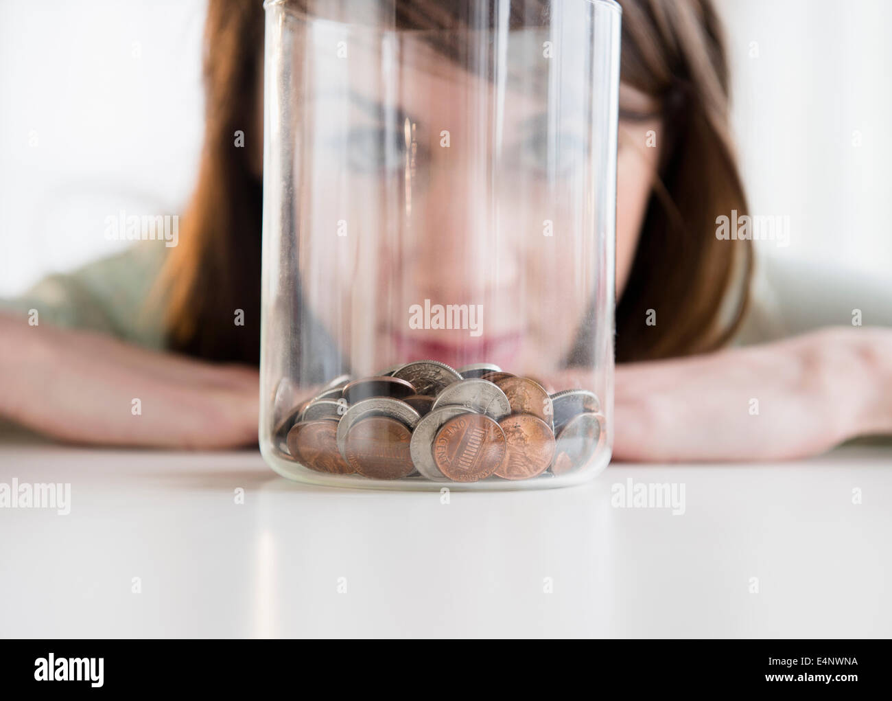 Giovane donna guardando le monete in vaso Foto Stock