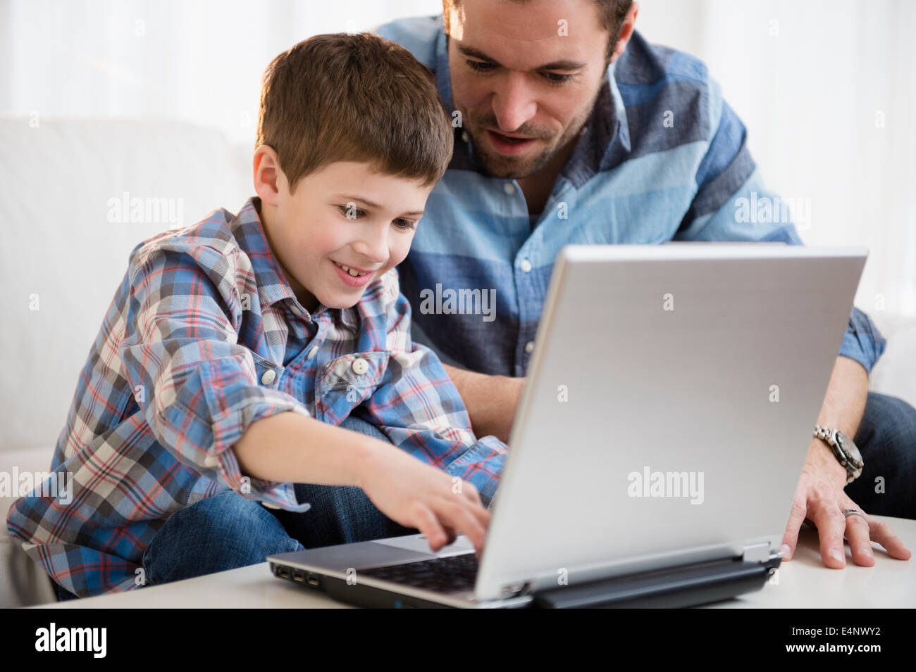 Padre lavora sul computer portatile con suo figlio (8-9) Foto Stock