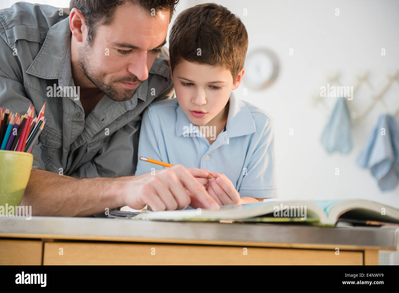 Padre aiutando il suo figlio (8-9) con i compiti Foto Stock