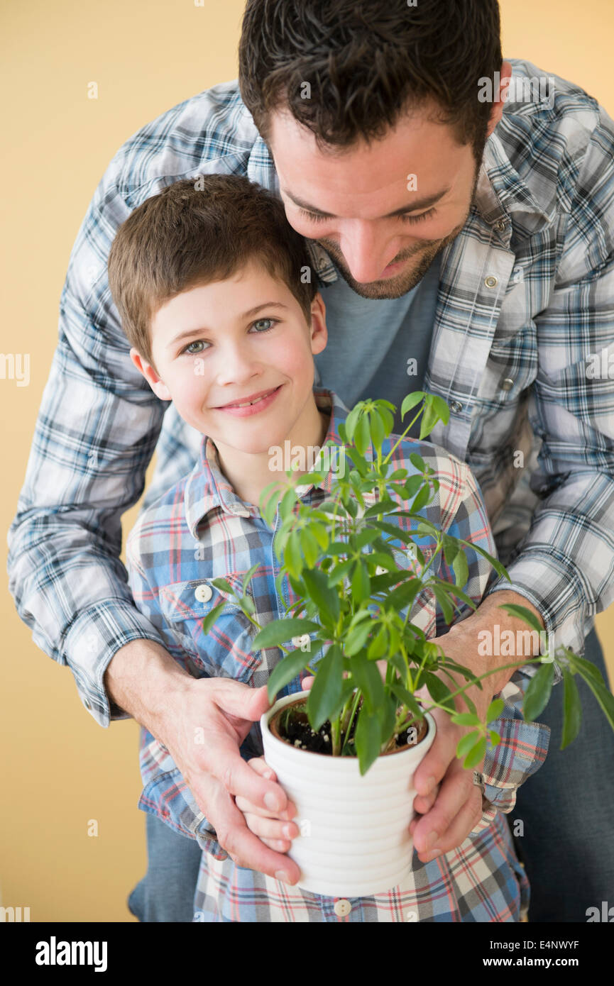 Padre e figlio (8-9) azienda pianta in vaso Foto Stock