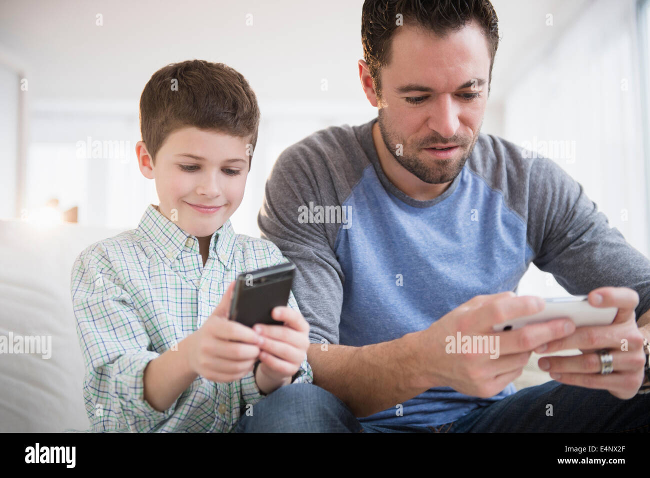 Padre e figlio (8-9) utilizzando il telefono cellulare Foto Stock