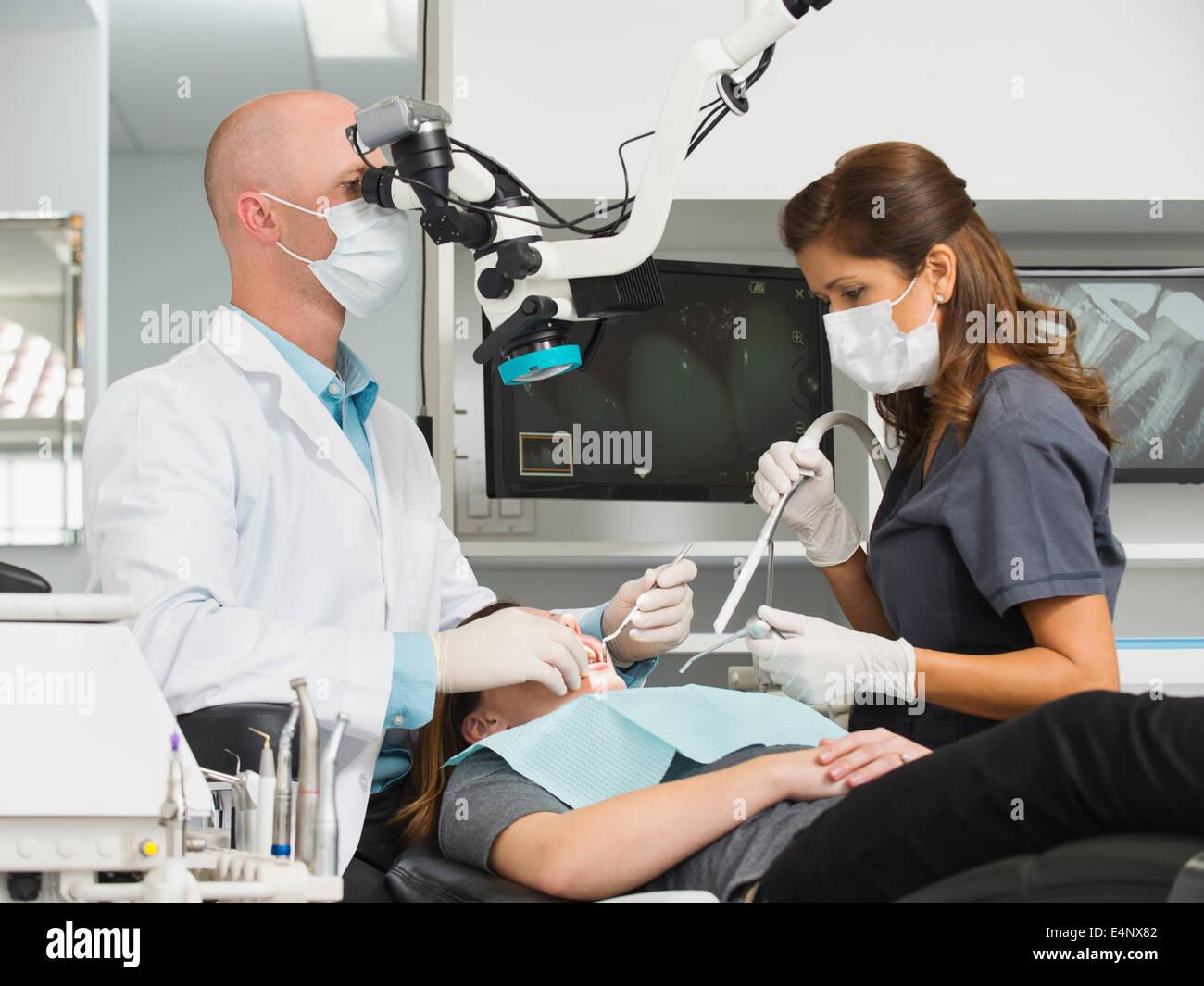 Dentista intervento sul paziente e mediante microscopio Foto Stock