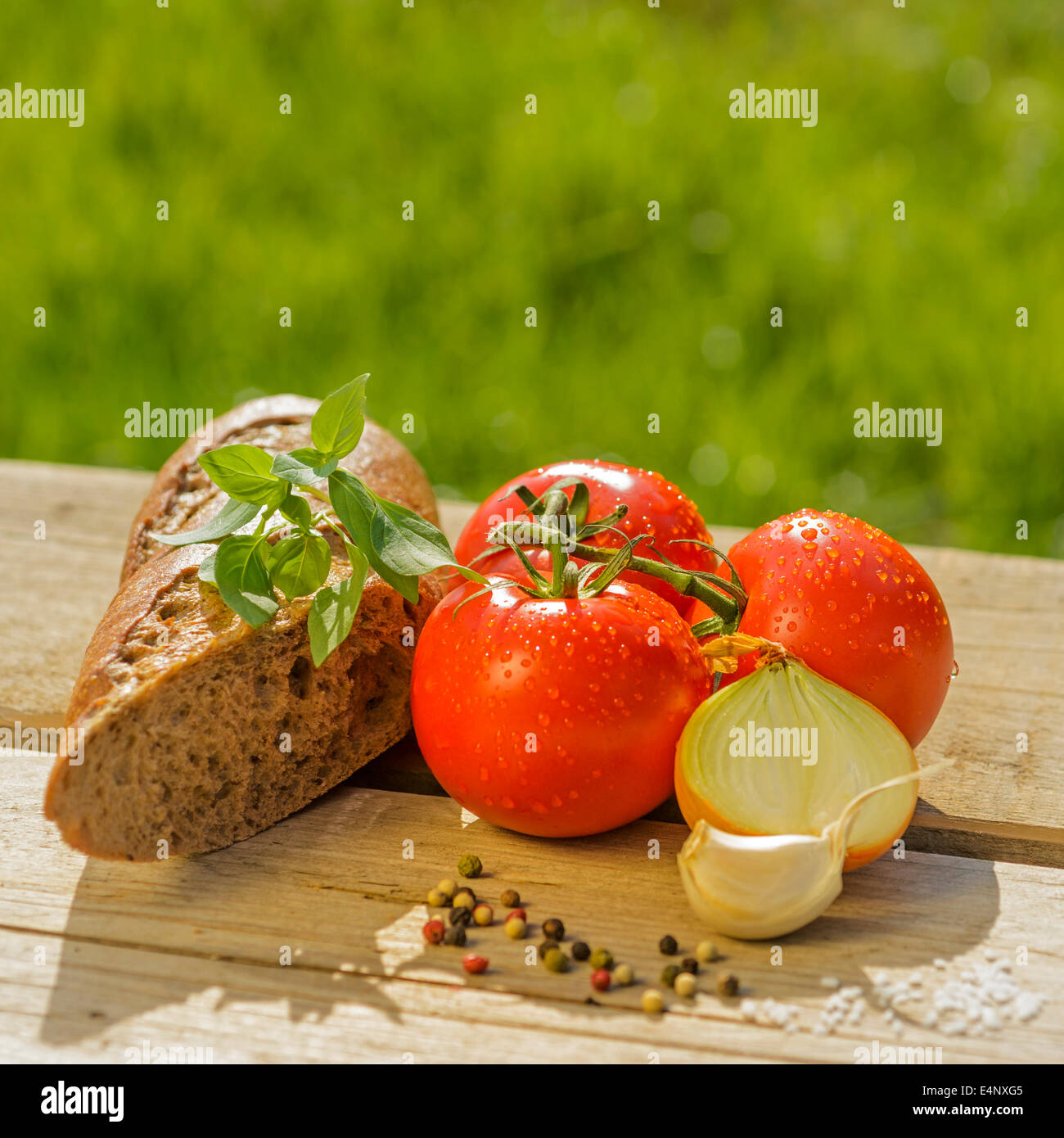 Al pomodoro e basilico cipolle con pepe e sale su un tavolo in legno all'esterno raccolto fresco vegetali cibo natura Foto Stock
