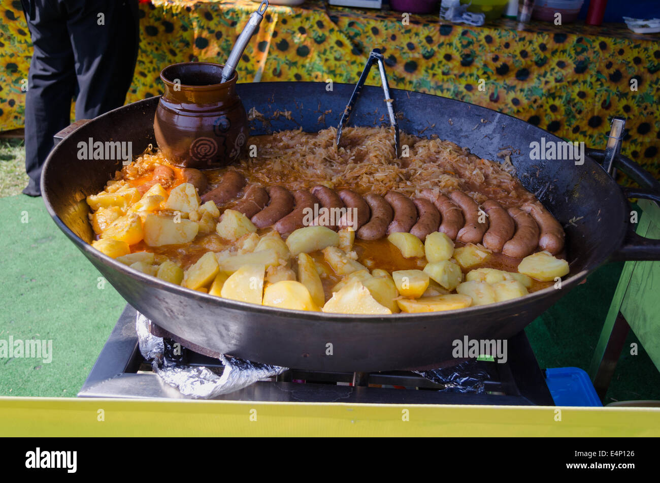 Patate, salsiccia e crauti cotti in una grande pentola di metallo. Deliziosi pasti organici in fiera rurale celebrazione. Foto Stock