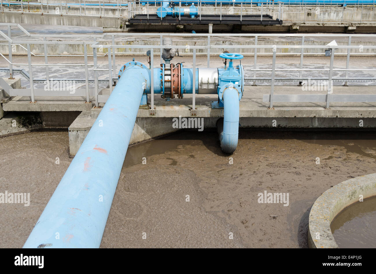 Blue rubinetto rubinetto gate e tubi in impianto di trattamento delle acque e il liquido sporco di bolla in background. Foto Stock