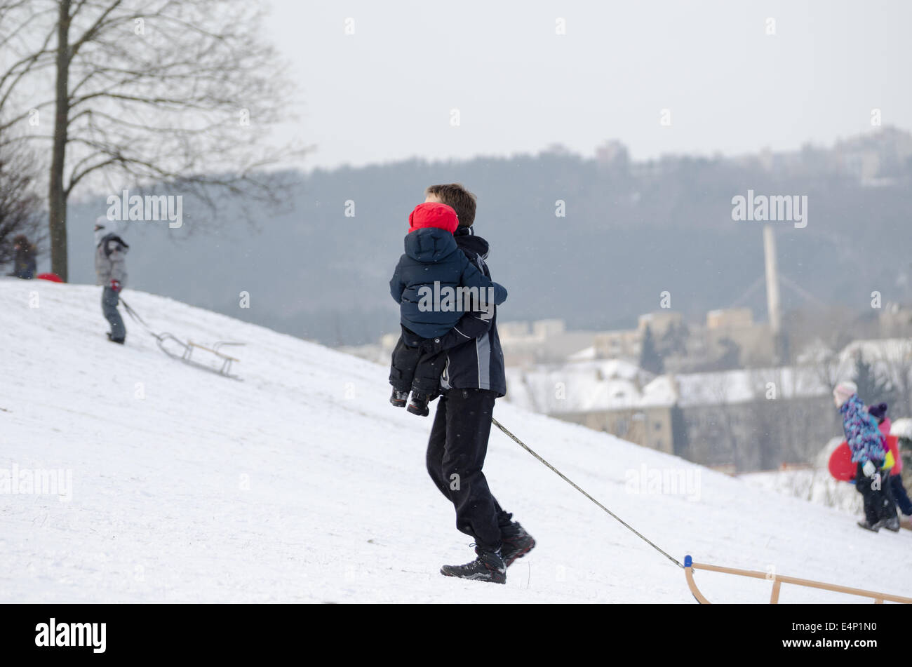 Padre con bambino salire la collina innevate in bel tempo invernale Foto Stock
