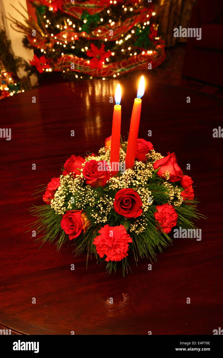 Natale Decorazioni per la tavola con Red Rose, garofani e candele, albero di Natale in background Foto Stock