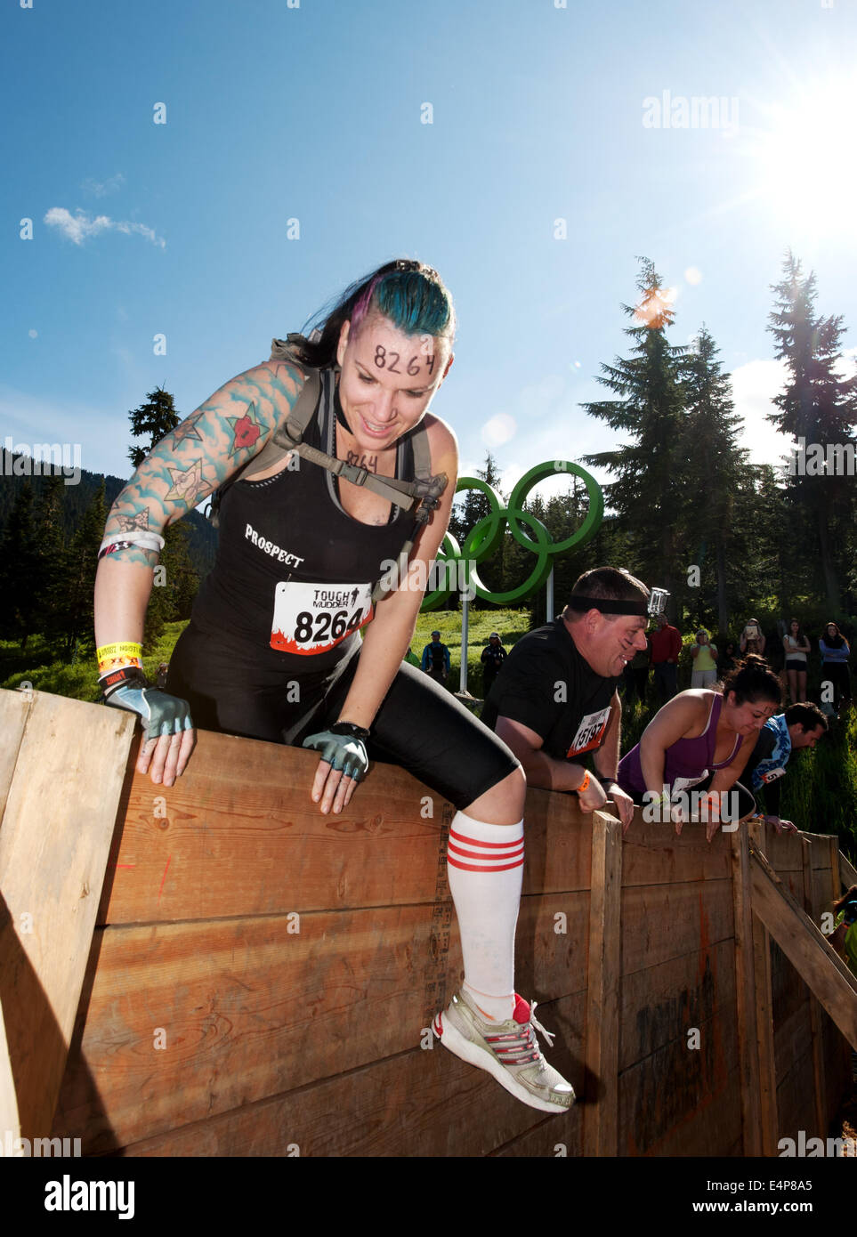 Una donna si arrampica su una parete al Whistler Vancouver dura Mudder evento. Foto Stock