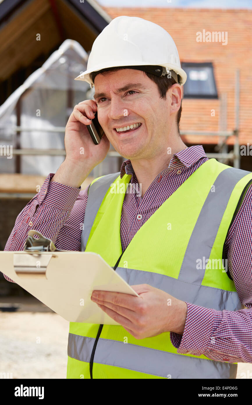 Architetto in cantiere utilizzando il telefono cellulare Foto Stock