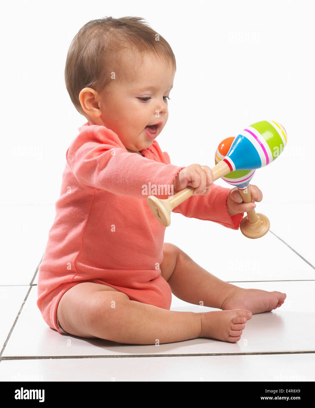 Baby girl (8 mesi) giocando con le maracas Foto Stock