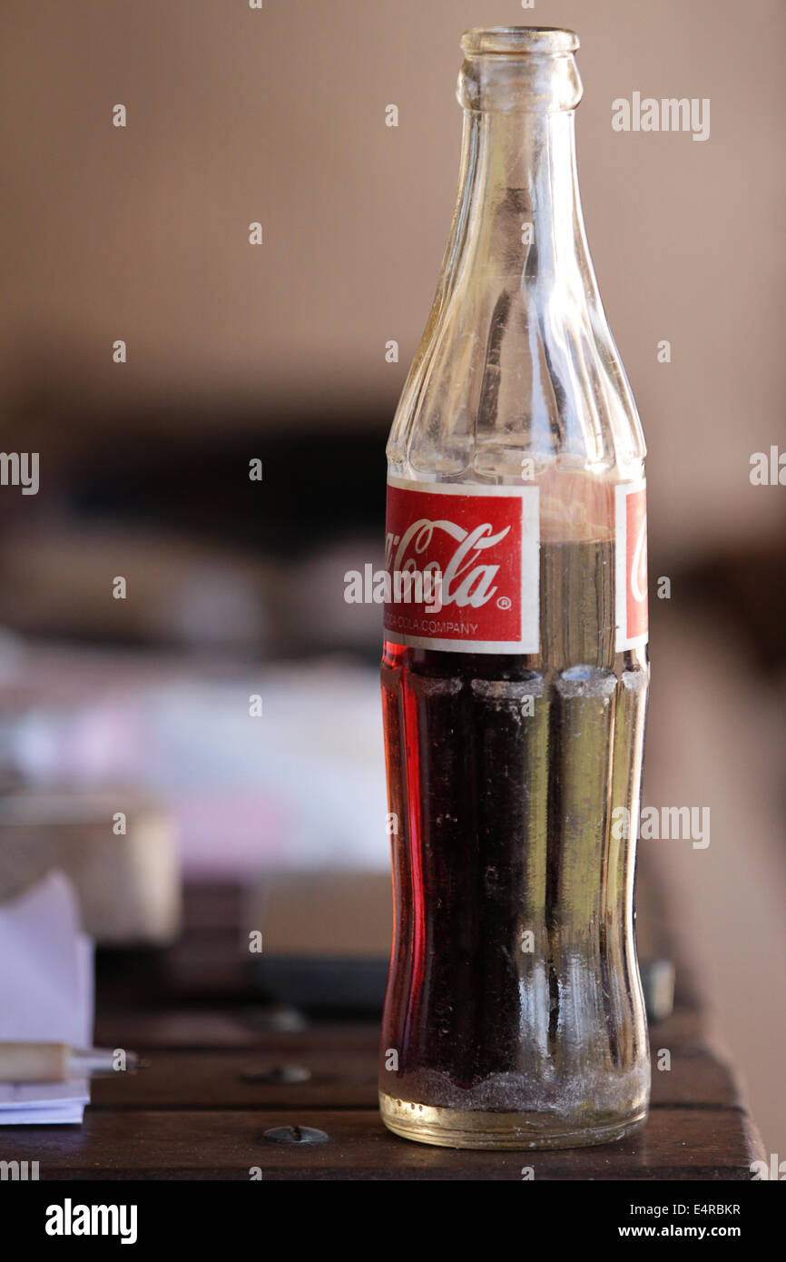Mezzo bicchiere pieno coca-cola bottiglia su una tavola di legno Foto Stock