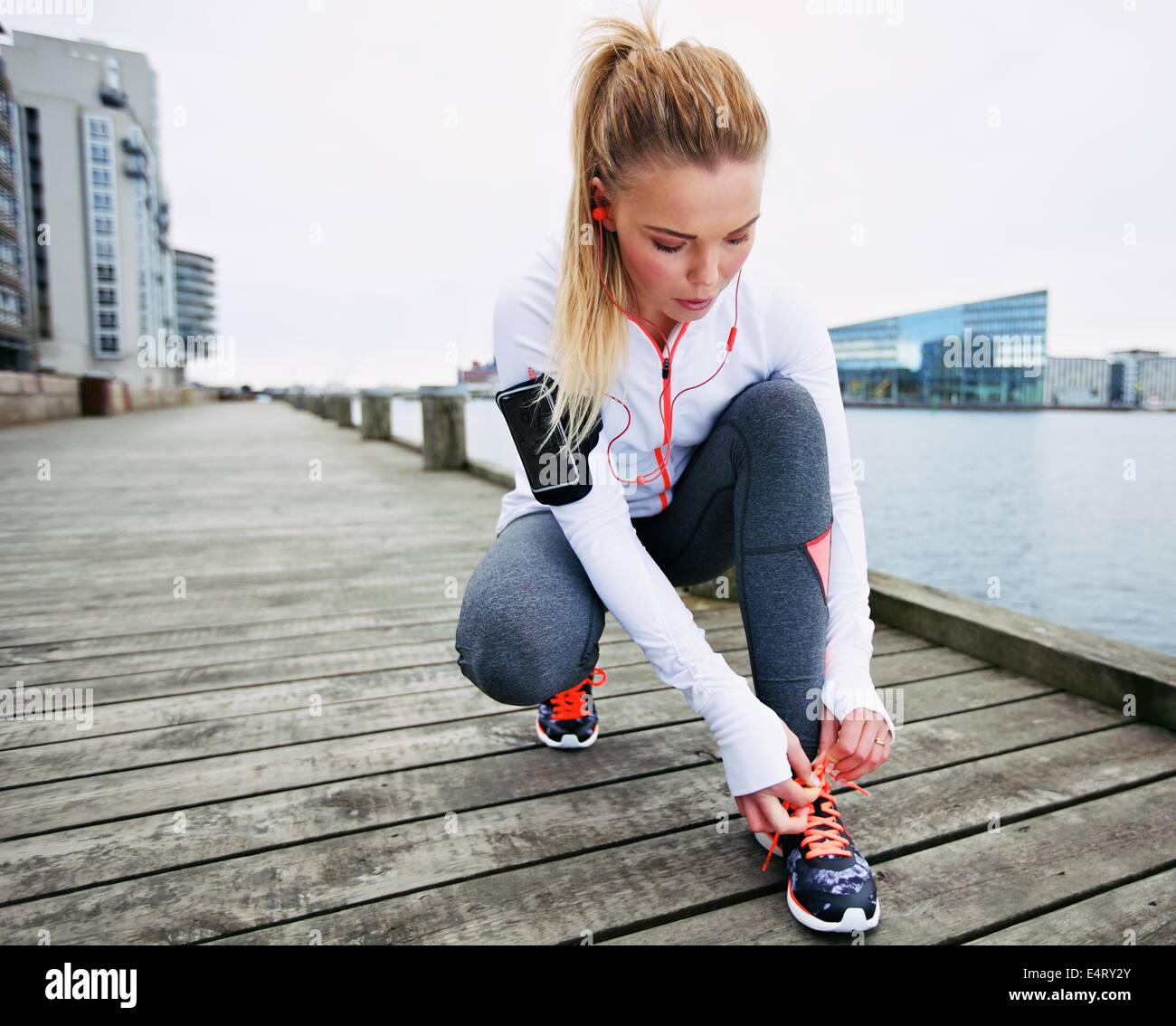 Montare e sportività giovane donna la sua legatura lacci prima di correre. Runner la sua legatura lacci delle scarpe mentre la formazione esterna. Foto Stock